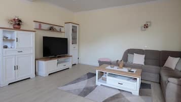 Una sala de estar con televisor, sofá, mesa de centro y muebles de almacenaje.