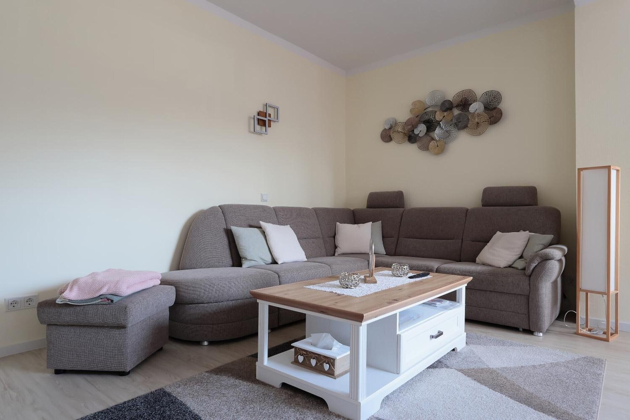 A living room with a sectional sofa, a coffee table, a side table, and a wall decor piece.