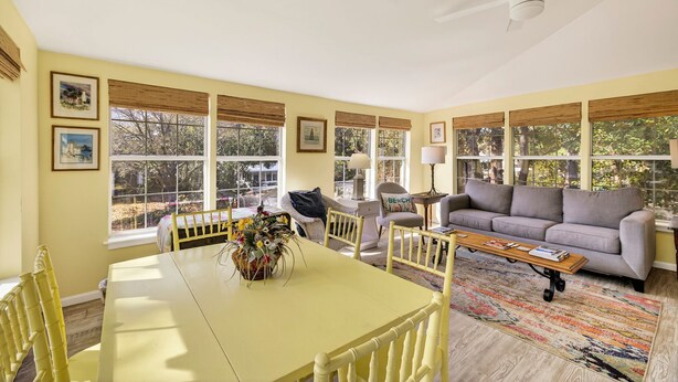 A bright room with a yellow table, a gray sofa, and a ceiling fan. - Magical Coastal Cottage, Short Walk to Beach by Tybee Cottages (Tybee Island)