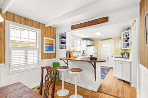 Eine Küche mit Holzausstattung, einer Bar mit Hockern und einem Fenster mit Jalousien.