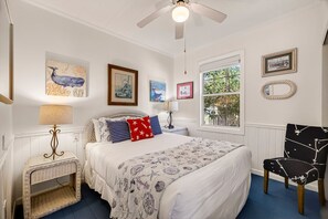 Ein Schlafzimmer mit einem Bett, einem Sessel, einem Fenster und Wandbildern.