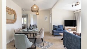 A modern living room with a flat-screen TV, a dining area with a table and chairs, and a sofa. - 3-bedroom eco villa in excellent Dilinata, family / friends friendly (Dilinata)