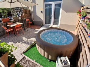 A hot tub in a backyard with a patio table and chairs, surrounded by potted plants and a small garden area. - "Il Pino"—a two-room apartment between Florence and Chianti. (Mela)