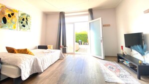 Quarto com cama, TV, mesa de console e porta de vidro deslizante para área externa.