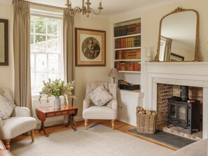 A cozy living room with a fireplace, a bookshelf, and a framed picture on the wall.