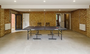 A ping pong table in a room with brick walls and a white door.
