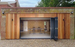A building with a wooden exterior, a brick wall, and a gravel ground.