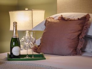 A bed with a green tray holding a bottle of champagne and two glasses.