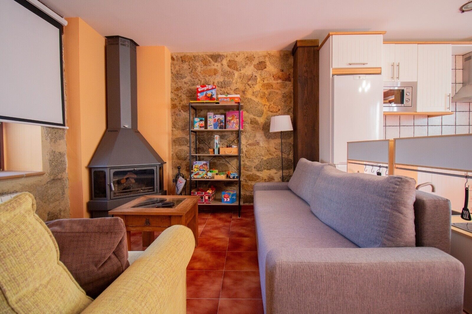 Un salon avec un mur en pierre, une cheminée, un canapé, une table basse et une bibliothèque.