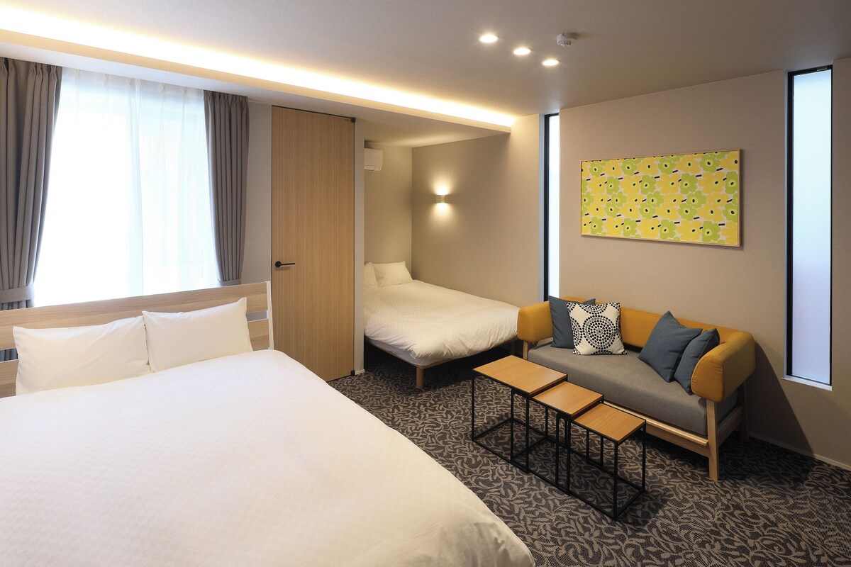 Une chambre d’hôtel avec un lit, un canapé, une petite table et un tableau au mur.