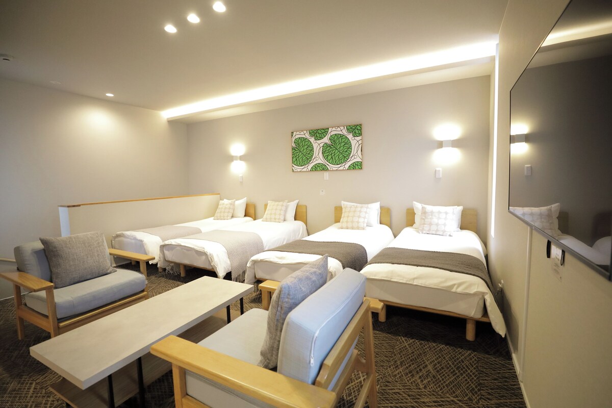 Une chambre d’hôtel avec quatre lits, deux canapés, une table et un miroir.
