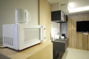 Un microondas blanco sobre una encimera de madera en una cocina moderna con un televisor de pantalla plana montado en la pared.