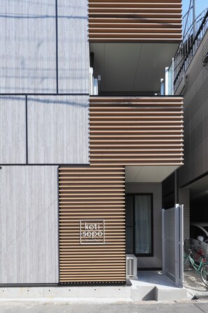 Un bâtiment moderne avec une façade à lattes de bois, une entrée bien visible et un vélo garé à l’extérieur.