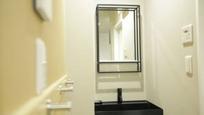 A bathroom with a mirror, a sink, and a wall-mounted thermostat. - Koti Sopo Universal Bay 2 by Liaison (Osaka)