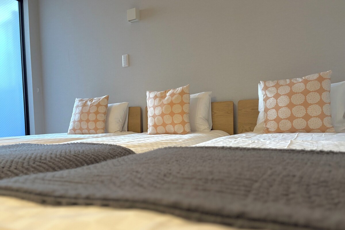 Une chambre d’hôtel avec un grand lit, plusieurs oreillers, une tête de lit et une fenêtre.