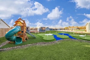 A playground with a slide and a small building, a golf course with flags, and a clear blue sky. - Le Bateau 2 - A Unique Stay by San Jacinto River (Highlands)
