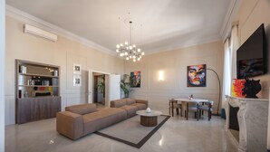 Una sala de estar moderna con un sofá seccional, una mesa de centro redonda, un comedor con mesa y sillas, y una chimenea.