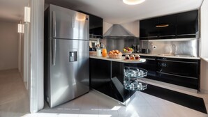 Una cocina moderna con electrodomésticos de acero inoxidable, armarios negros y un enfriador de vino de vidrio.