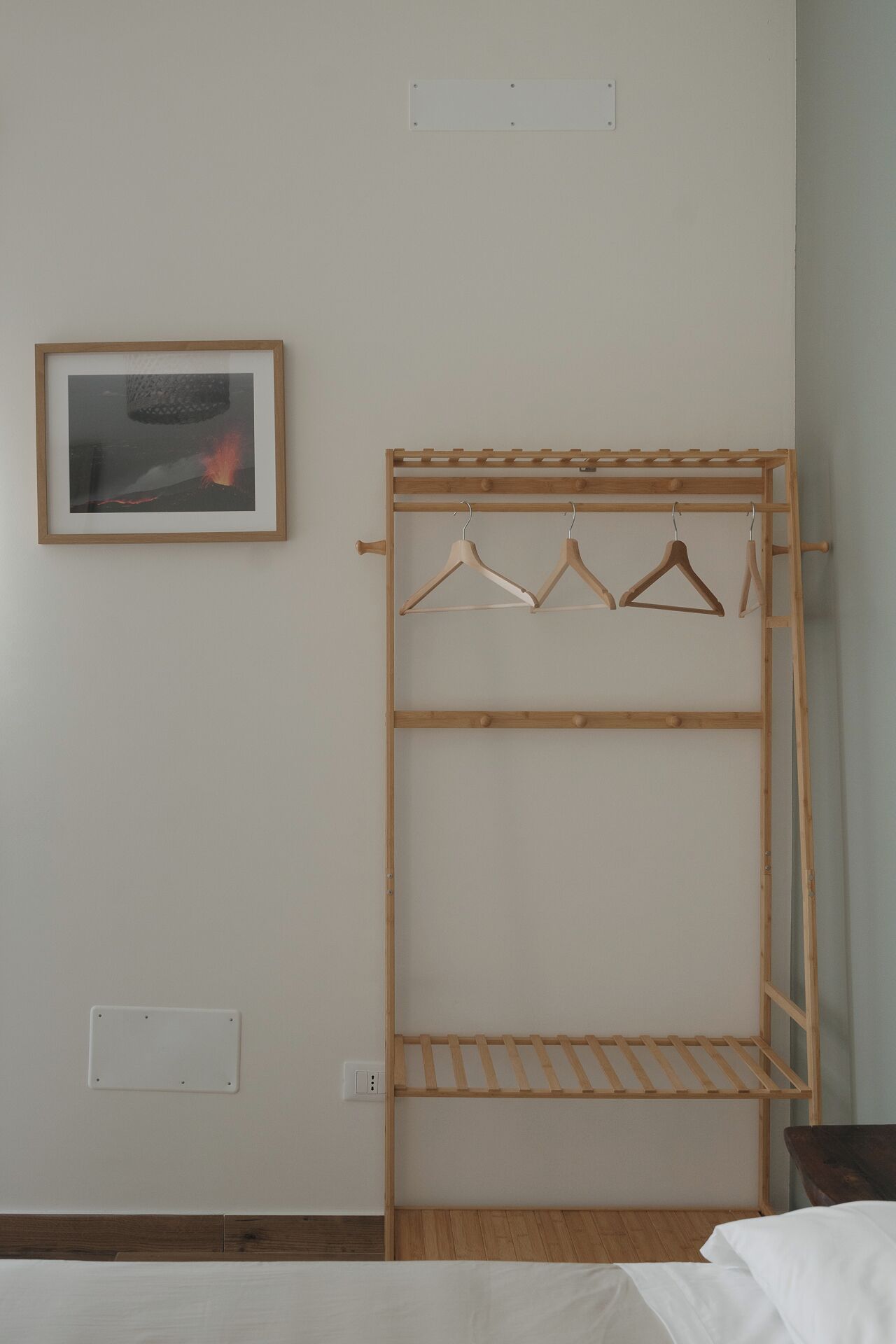 Ein Zimmer mit einem Holzschrank, einem gerahmten Bild an der Wand und einem Bett.