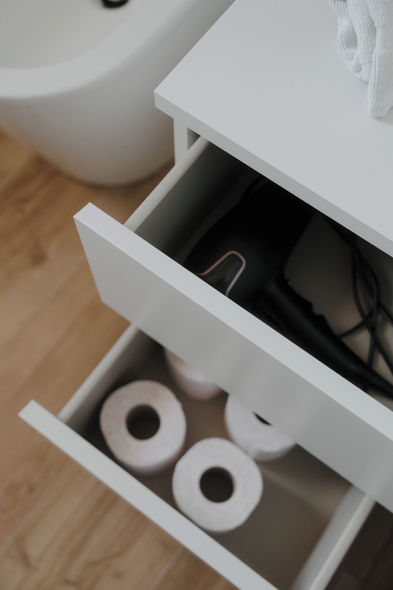 A white drawer with toilet paper rolls inside.