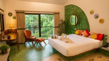 Une chambre d’hôtel comprenant un lit, un bureau, une chaise, une fenêtre avec des rideaux, un mur d’accent vert et une petite table avec une lampe.