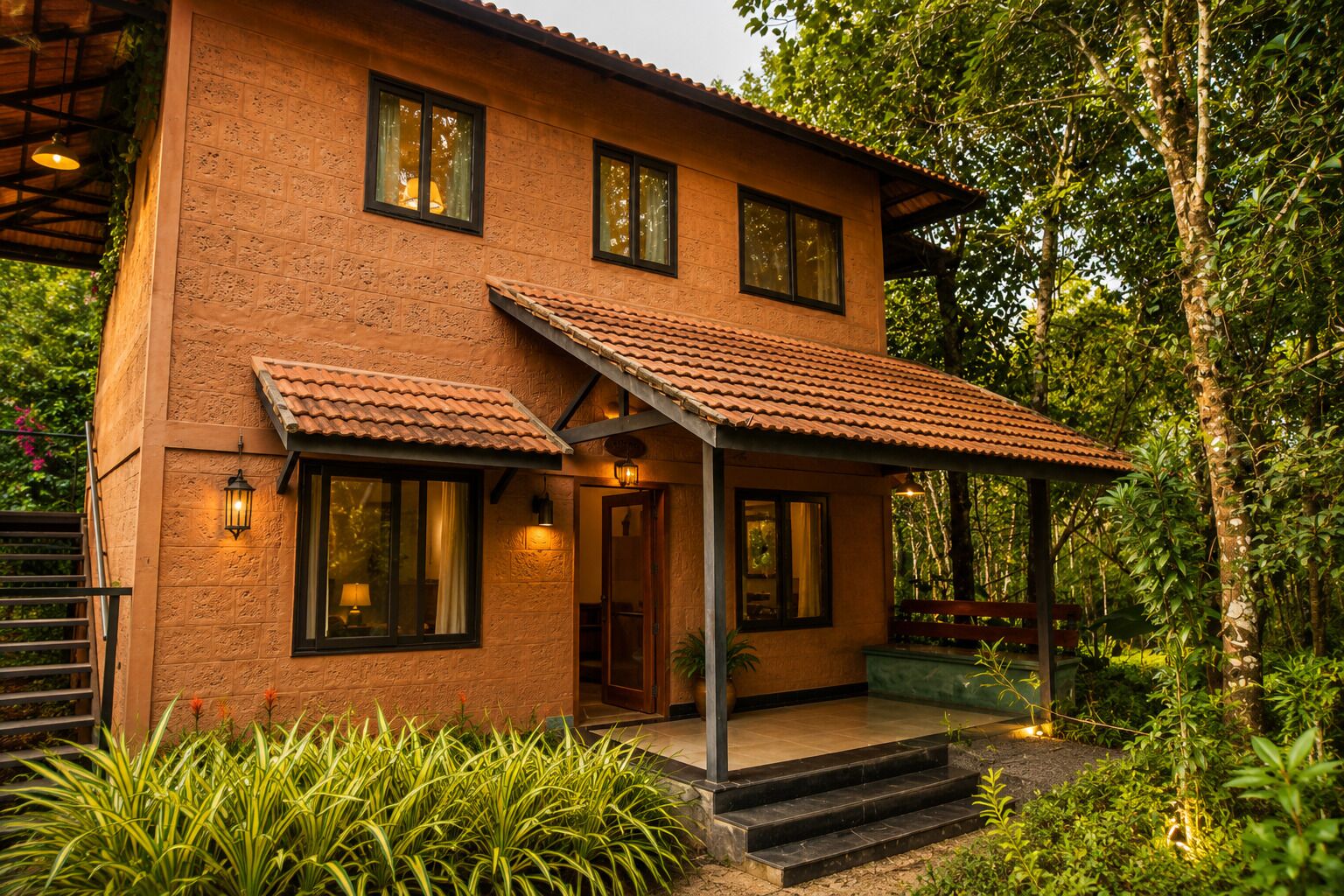 A two-story house with a covered porch, surrounded by lush greenery.