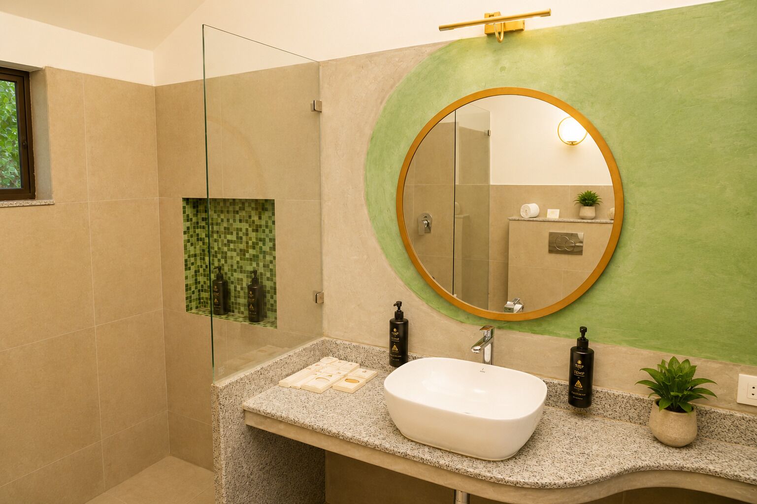 Un baño moderno con cabina de ducha de vidrio independiente, un lavamanos independiente sobre encimera de granito y un espejo redondo con marco dorado.