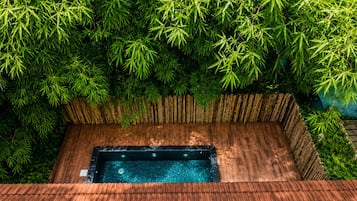 A hot tub surrounded by bamboo foliage and a wooden deck.