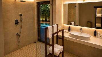 Un baño moderno con ducha a ras de suelo, un espejo grande y un lavabo.