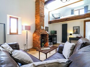 A living room with a brick fireplace, leather sofa, and a dining table.