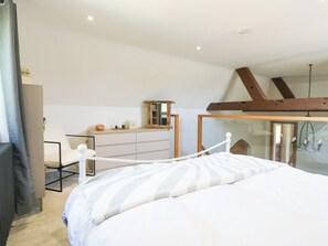 Une chambre à coucher comprenant un lit, un bureau, une chaise, une commode et un miroir.