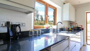 Una cocina moderna con encimera negra, una ventana con vistas a árboles y un fregadero.