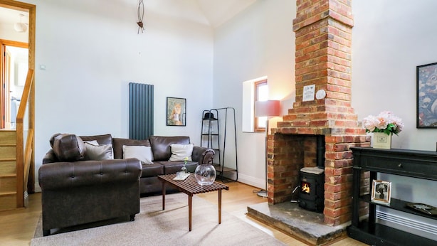 A living room with a brick fireplace, a sofa, a coffee table, and a lamp.