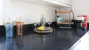 Una encimera de cocina con una cafetera, un exprimidor y un frutero.