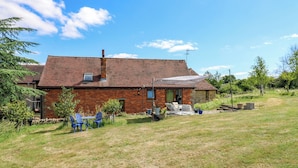 A brick house with a patio, a swing set, and a lawn.