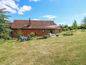 Une maison en briques avec un patio, une balançoire et une pelouse.
