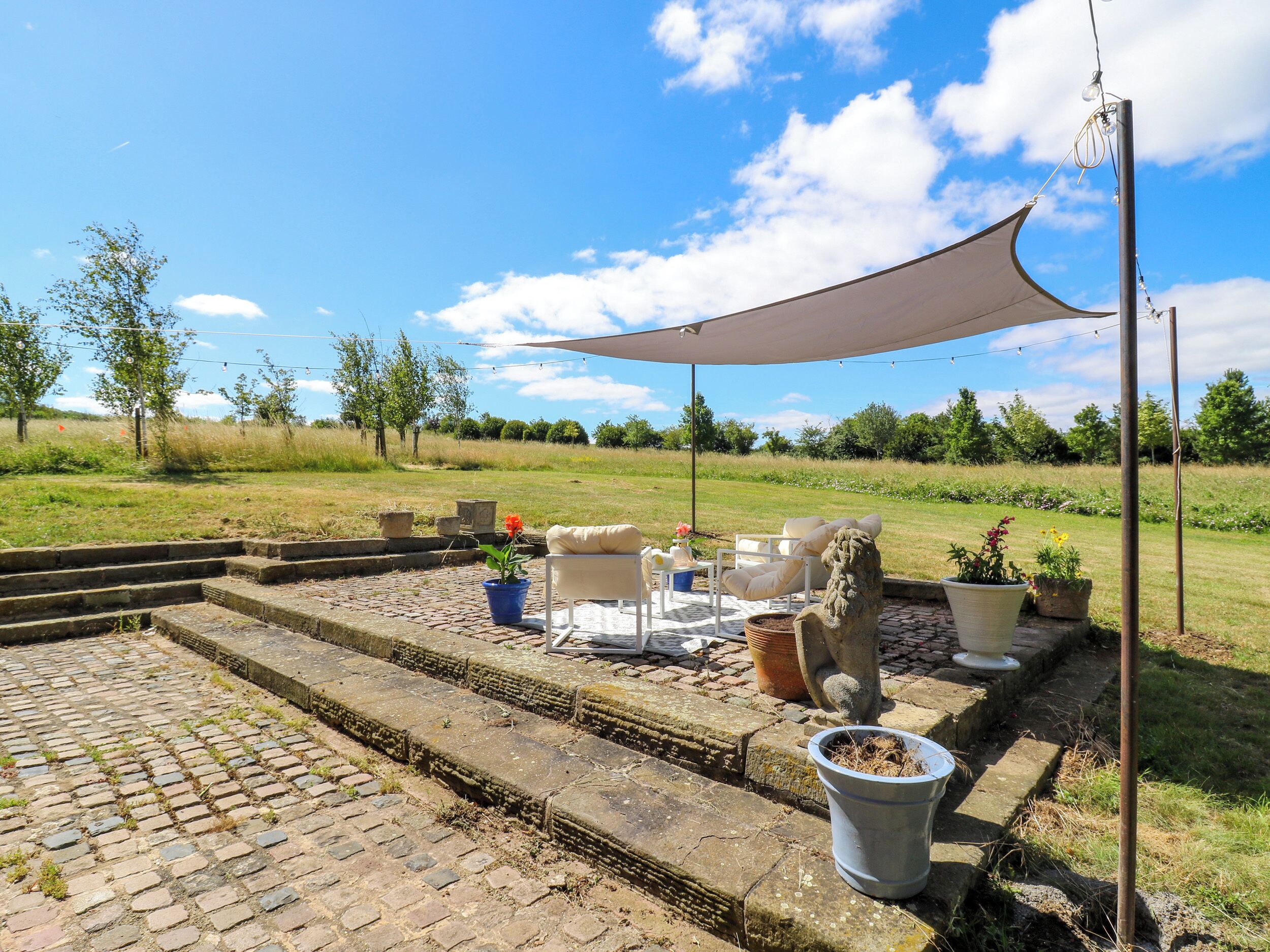 Un patio con muebles de exterior, una escalera de piedra y plantas en macetas.