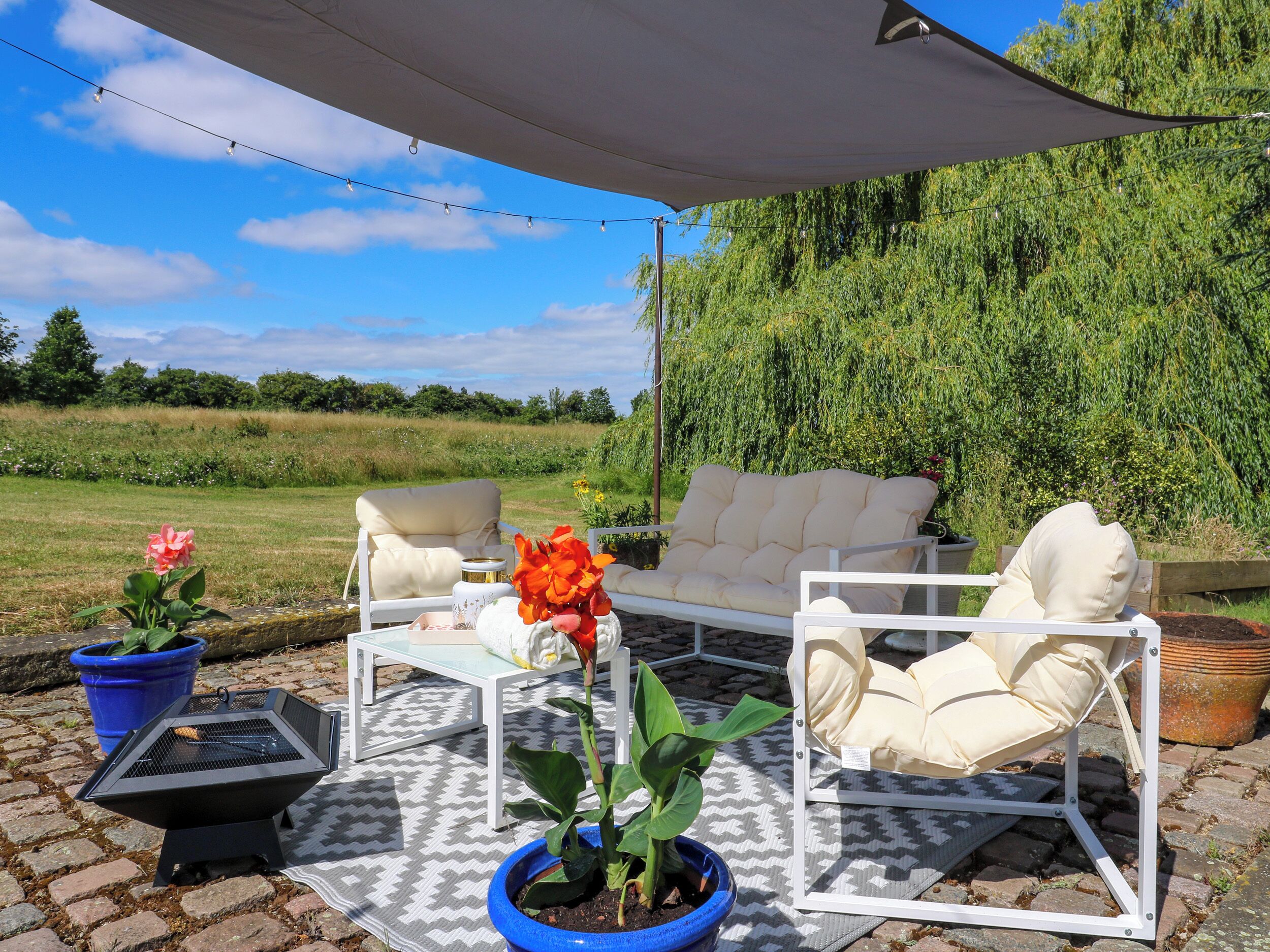 An outdoor seating area with a white sofa, a small table, and a potted plant.