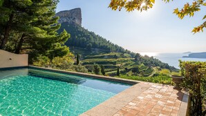 A pool with clear water, surrounded by terraced gardens and a view of a mountain and the sea. - Les Hauts de Cassis in Cassis (Cassis)