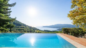 A clear blue swimming pool with terracotta tiles, surrounded by lush greenery and a scenic view of a lake and mountains. - Les Hauts de Cassis in Cassis (Cassis)