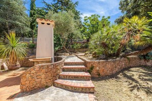 A stone staircase leading to a white structure, surrounded by lush greenery and a stone wall.