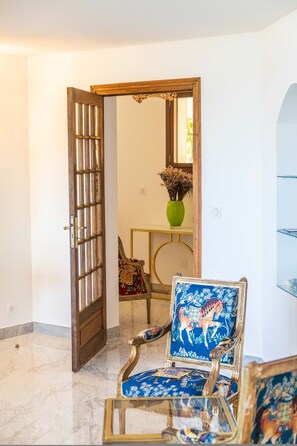 An open door leading to a room with a chair, a vase, and a mirror.
