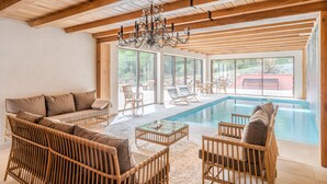 A spacious indoor area with a pool, wicker furniture, and large windows. - Le Buchwald in Dambach (Dambach)