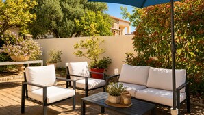 An outdoor patio with a sofa, chairs, and a table, surrounded by potted plants and trees. - Bas de Villa Lola Avec Piscine (Six-Fours-les-Plages)