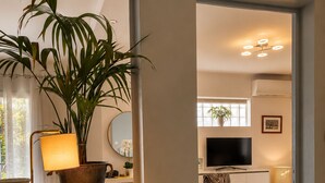 A modern living room with a large potted plant, a round mirror, a flat-screen TV, and a zebra-patterned chair. - Bas de Villa Lola Avec Piscine (Six-Fours-les-Plages)