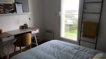 A bedroom with a bed, a desk, a chair, a window with a view, and a ladder.