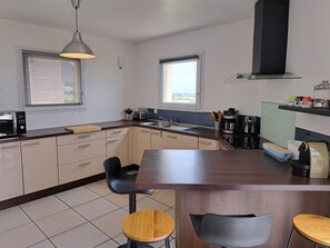 A modern kitchen with a central island, a built-in oven, and a coffee machine. - Panoramic Holiday Villa With Sea Views in Telgruc-sur-mer (Telgruc-sur-Mer)