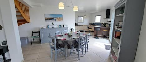 Une cuisine moderne avec un coin repas, comprenant un escalier, un grand îlot central et une vue sur l’extérieur.