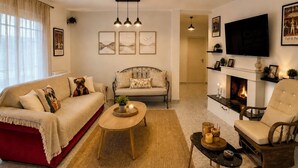 Una sala de estar con sofá, sillón, mesa de centro, chimenea y obras de arte en las paredes.
