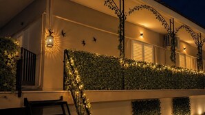 Un edificio con balcón techado, luces decorativas y una lámpara en la pared.